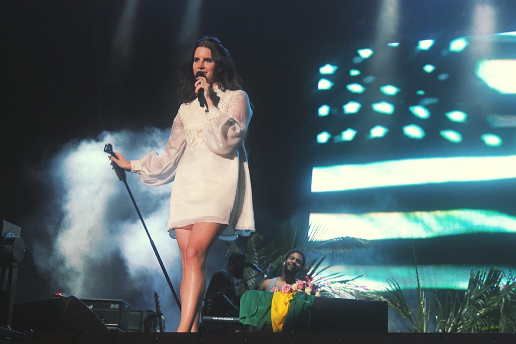 A picture of Lana Del Rey performing with an image of the American flag behind her