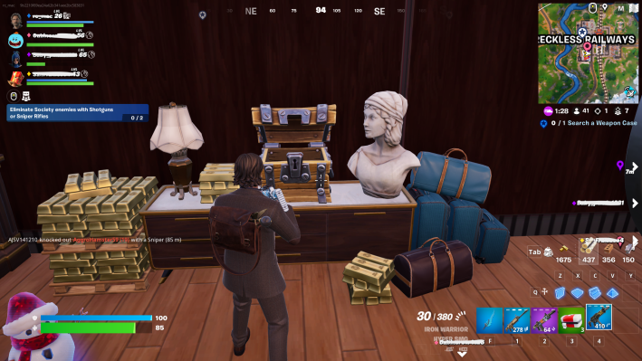 Alan Wake in Fortnite standing before a pile of gold bars and a treasure chest. There's a white stone bust and a lamp on either side of the treasure chest