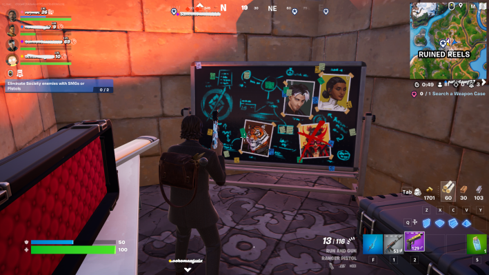 Alan Wake in Fortnite, staring at a chalkboard covered in blue writing. Photographs of various Fortnite characters are taped on the chalkboard.