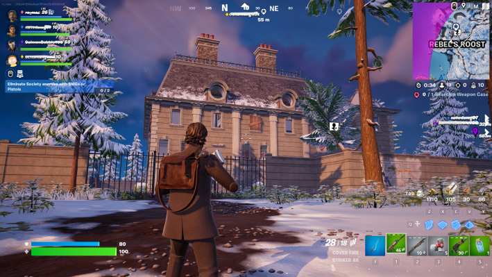 Alan Wake in Fortnite, staring at a white brick building. Two round windows are set into the building's roof. There is snow on the ground around him