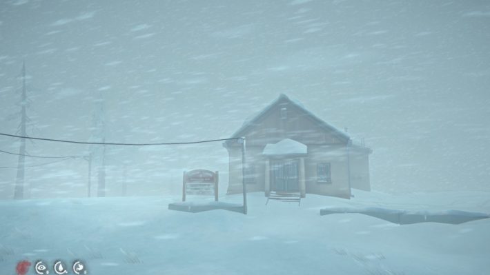 A screenshot from "The Long Dark:" a brown building with a sign out front, as seen in a blizzard