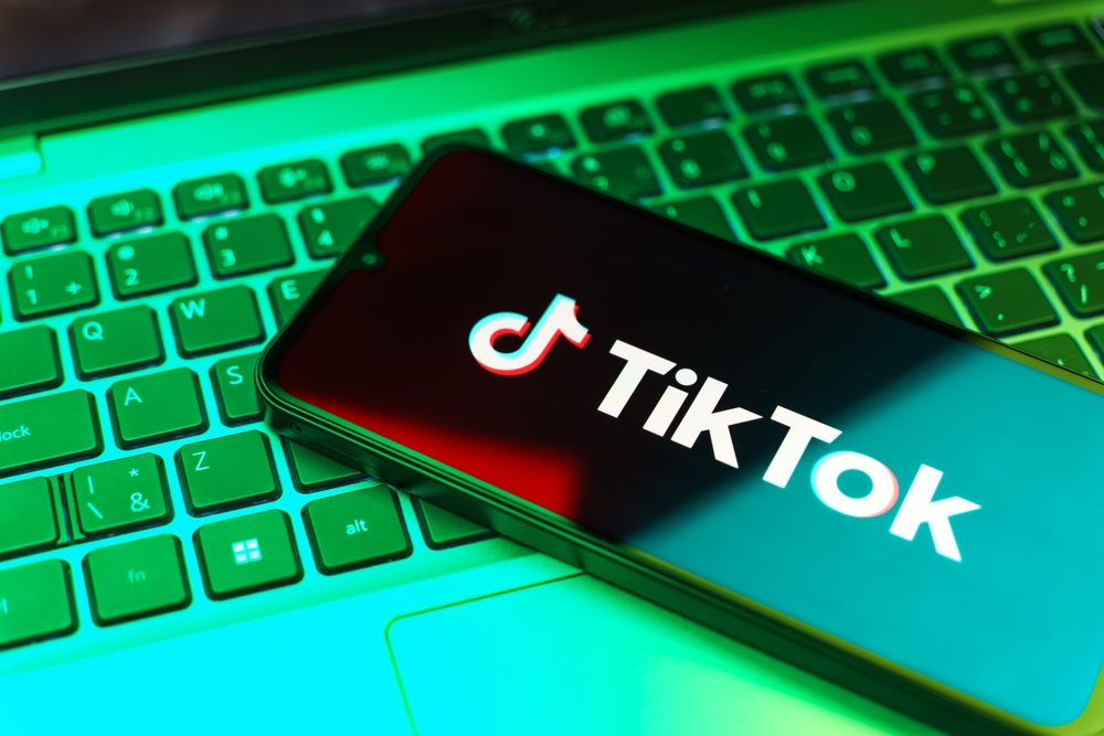 A phone with the word "TikTok" on top of a computer