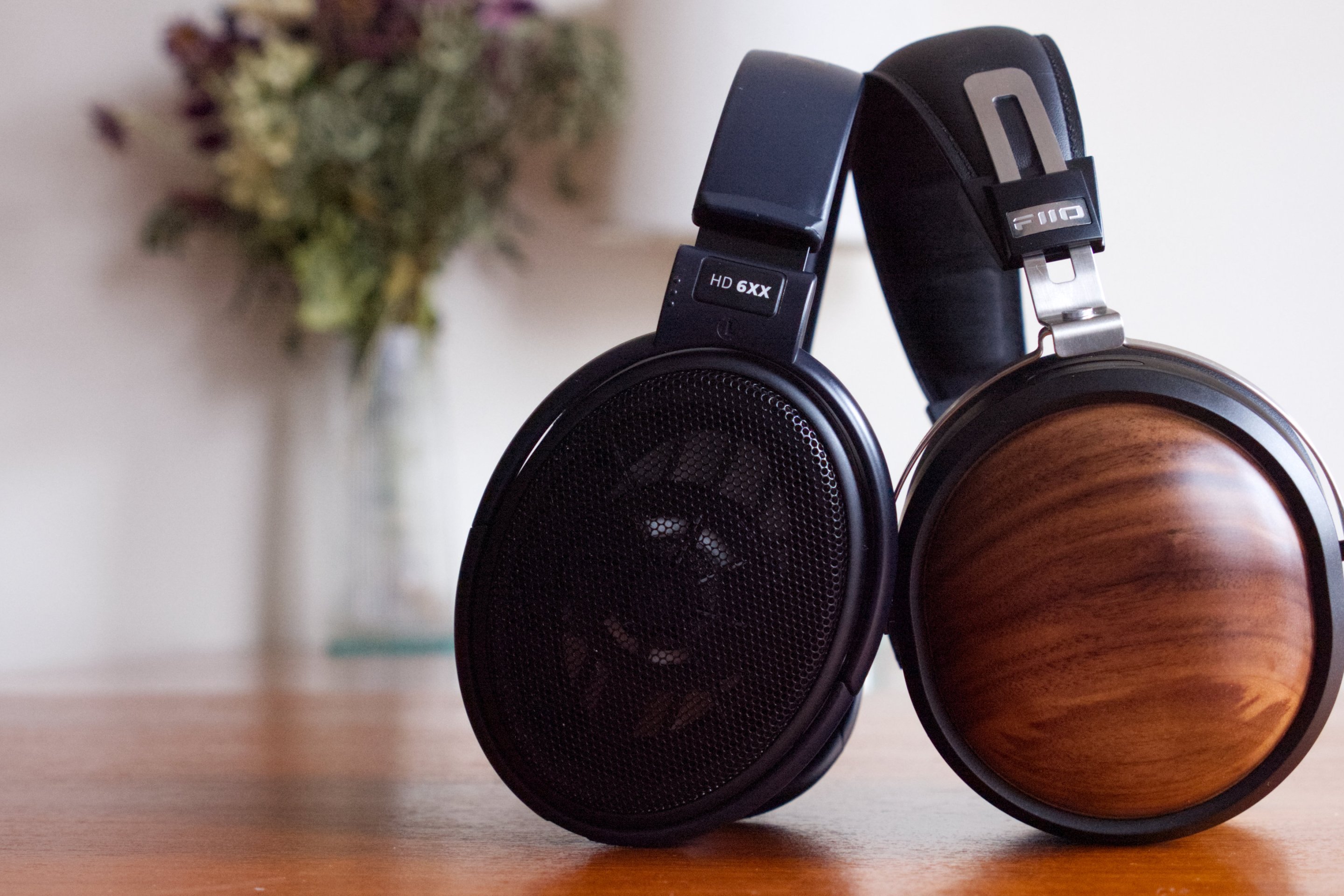 The Sennheiser HD 6XX and FiiO FT1 next to each other on a wood table, with a