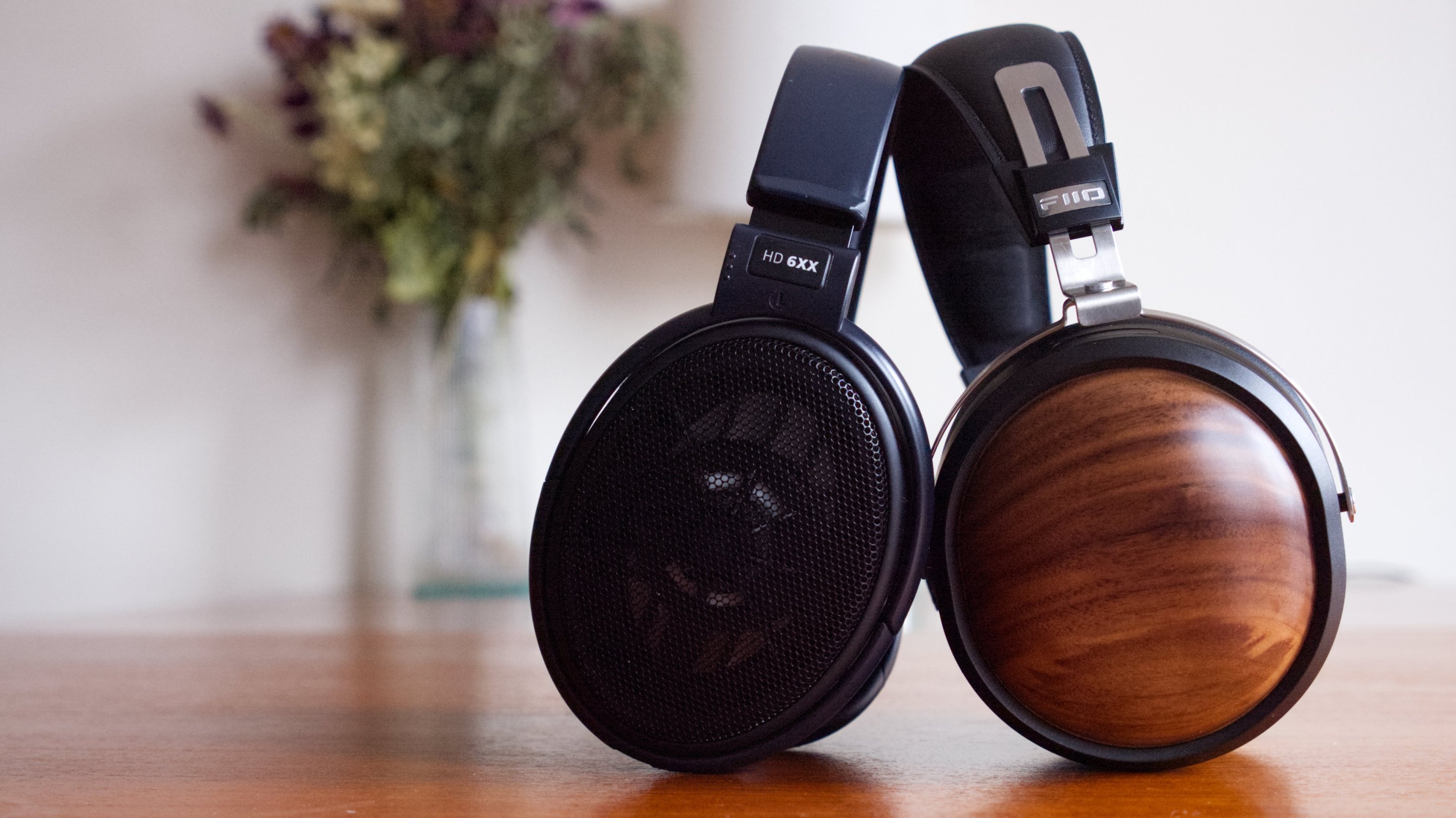 The Sennheiser HD 6XX and FiiO FT1 next to each other on a wood table, with a