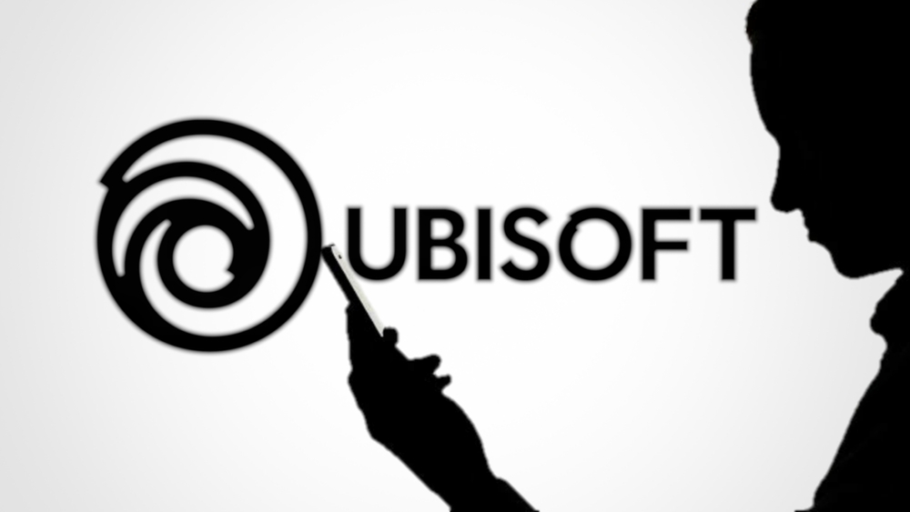 Jakarta - June 12,2023: Ubisoft Entertainment SA logo on blurred background with silhouette of man using smartphone. is a French video game publisher headquartered in Saint-Mande